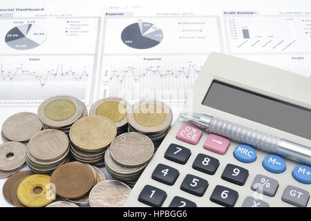 Rechner und Stapel von Münzen auf weißem Papier finanzielle Graphen Stockfoto