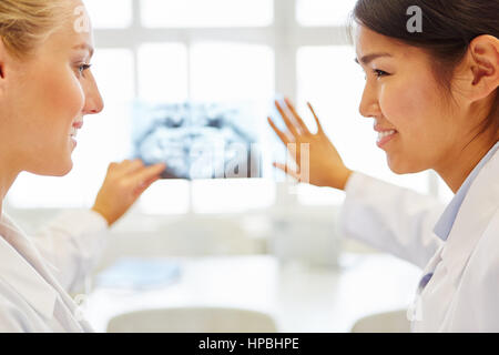 Zwei junge Frauen diagnostizieren wie Ärzte in Teamarbeit Röntgenbild diskutieren Stockfoto