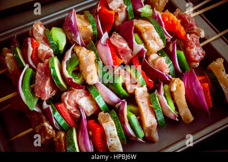 Geordneten Reihen des Fleisches auf hölzerne Spieße. Verschiedene bunte und gesunde Gemüse Grillen in einen Grill. Shish Kebab mit Champignons, Paprika, Kirsche Toma gemacht Stockfoto