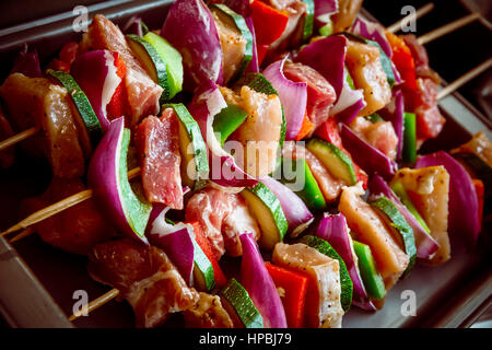 Geordneten Reihen des Fleisches auf hölzerne Spieße. Verschiedene bunte und gesunde Gemüse Grillen in einen Grill. Shish Kebab mit Champignons, Paprika, Kirsche Toma gemacht Stockfoto