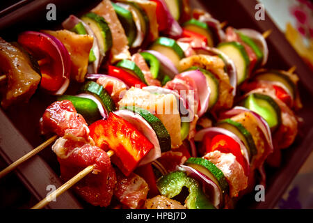 Geordneten Reihen des Fleisches auf hölzerne Spieße. Verschiedene bunte und gesunde Gemüse Grillen in einen Grill. Shish Kebab mit Champignons, Paprika, Kirsche Toma gemacht Stockfoto