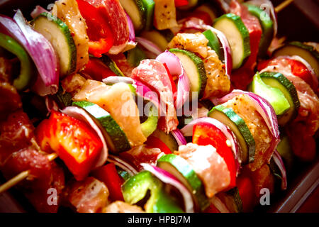 Geordneten Reihen des Fleisches auf hölzerne Spieße. Verschiedene bunte und gesunde Gemüse Grillen in einen Grill. Shish Kebab mit Champignons, Paprika, Kirsche Toma gemacht Stockfoto