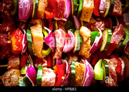 Geordneten Reihen des Fleisches auf hölzerne Spieße. Verschiedene bunte und gesunde Gemüse Grillen in einen Grill. Shish Kebab mit Champignons, Paprika, Kirsche Toma gemacht Stockfoto