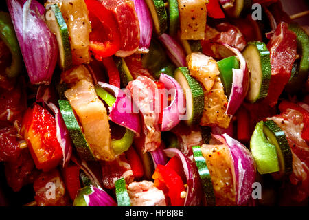 Geordneten Reihen des Fleisches auf hölzerne Spieße. Verschiedene bunte und gesunde Gemüse Grillen in einen Grill. Shish Kebab mit Champignons, Paprika, Kirsche Toma gemacht Stockfoto