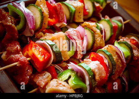 Geordneten Reihen des Fleisches auf hölzerne Spieße. Verschiedene bunte und gesunde Gemüse Grillen in einen Grill. Shish Kebab mit Champignons, Paprika, Kirsche Toma gemacht Stockfoto