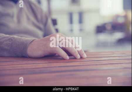 Hand des jungen Mannes mit einem goldenen Hochzeit Ring auf Holztisch, der Hintergrund jedoch unscharf Stockfoto