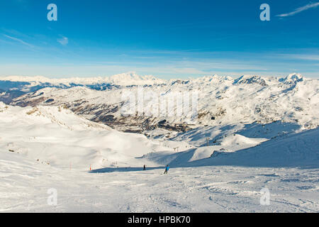 Skifahrer auf einer Skipiste piste im Winter Alpine Mountain Resort mit Dorf im Hintergrund Stockfoto