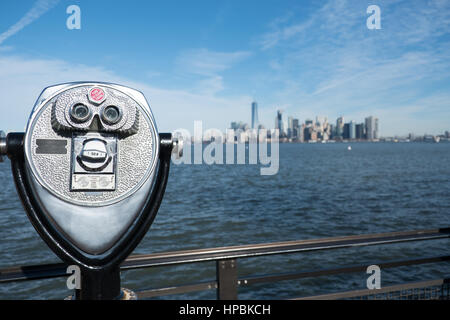 Skyline von Manhattan und New York Harbor aus der Ferne auf Liberty Island gesehen.  Turm-Viewer-Fernglas auf einem drehbaren stehen sieht, wie ein Gesicht in Foregrou Stockfoto