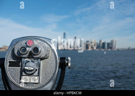 Nahaufnahme des Turms Viewer Fernglas mit unscharfen New Yorker Skyline im Hintergrund auf Liberty Island. Hafen von New York City und Manhattan s Stockfoto