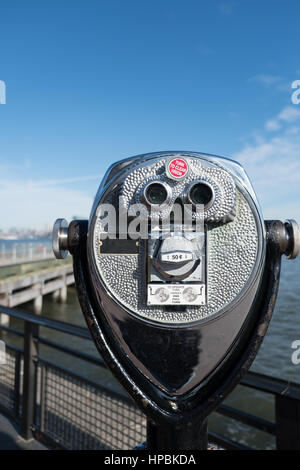 Turm Viewer Fernglas auf Liberty Island, Blick auf Manhattan, New York.  Pier und Manhattan Skyline in der Ferne. Geringe Schärfentiefe, fo Stockfoto