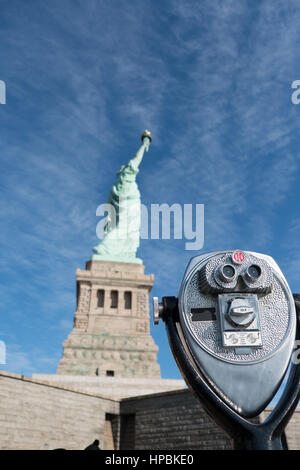 Turm-Viewer Fernglas im Fokus, Statue of Liberty im Hintergrund verschwommen, geringe Schärfentiefe.  Freiheitsstatue auf Liberty Island in Profil Stockfoto