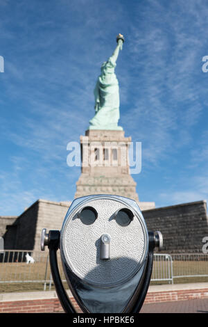 Alten Turm Viewer Fernglas im Vordergrund, der Freiheitsstatue im Hintergrund an einem sonnigen Tag mit blauem Himmel auf Liberty Island, Manhattan, New York C Stockfoto