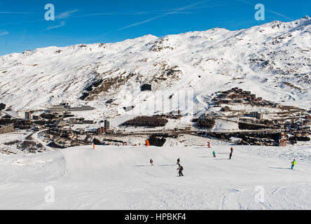 Skifahrer auf einer Skipiste piste im Winter Alpine Mountain Resort mit Dorf im Hintergrund Stockfoto