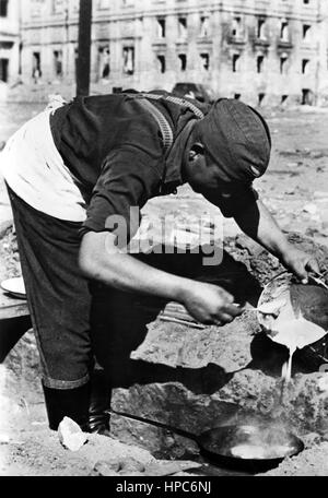 Die Originalfotografie, aus der dieses digitale Bild gemacht wurde, liest auf dem Rücken die nationalsozialistische Propaganda vom 22. Oktober 1942: "Pfannkuchen an einem Bahnhof in Stalingrad. Der Koch einer Flak-Batterie bereitet das Mittagessen zu - heute sind es Pfannkuchen.“ Fotoarchiv für Zeitgeschichte | weltweite Verwendung Stockfoto