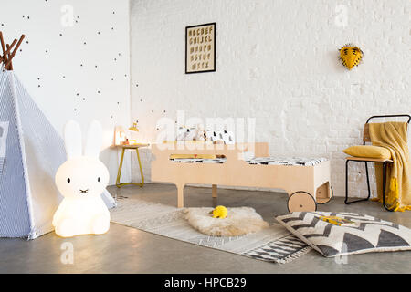 Ein Kinderbett in einem weißen Schlafzimmer mit Beton ausgegossen, ein Tipi und eine weiße Wand Stockfoto