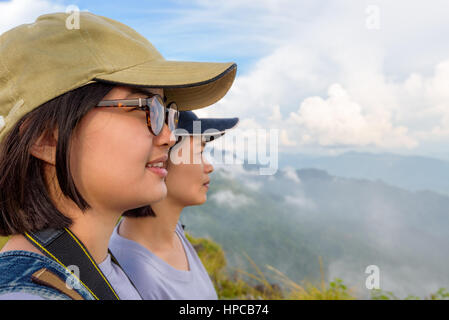 Gesicht-zwei junge Frauen-Wanderer, Mutter und Tochter glücklich lächelnd beim Phu Chi Fa schöne Landschaft Natur des Gebirges und des Himmels betrachten Stockfoto