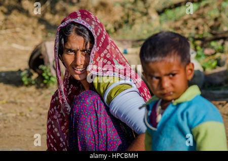 RAJASTHAN, Indien - 20. November 2016: Rajasthani arme Frau tragen Sari und traditionellen Ornamenten auf ihren Händen, ihrem kleinen Sohn im Vordergrund Stockfoto