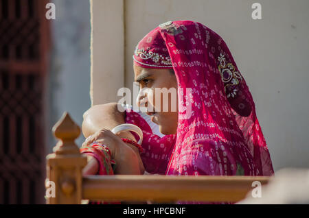 RAJASTHAN, Indien - 20. November 2016: Unidentified Rajasthani Frau wartet auf jemanden tragen bunte rote sari Stockfoto