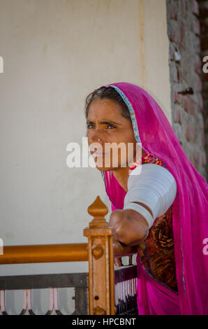 RAJASTHAN, Indien - 20. November 2016: Unbekannte ältere Rajasthani Frau wartet auf jemanden tragen Tracht und roten Sari mit ornament Stockfoto