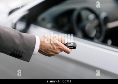 Geschäftsmann hält einen Autoschlüssel mit Fernbedienung und einen Knopf, er ist die Tür entriegeln, Hand hautnah Stockfoto