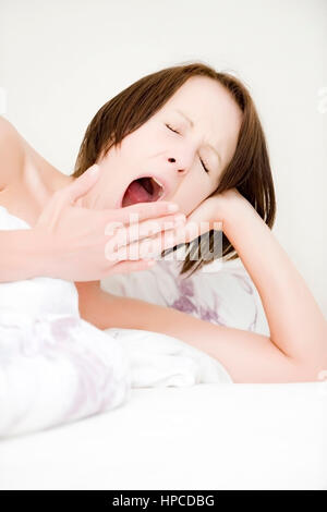 Model Release, Tagwache, so Frau Gaehnend Im Bett - Frau Gapeing im Bett Stockfoto