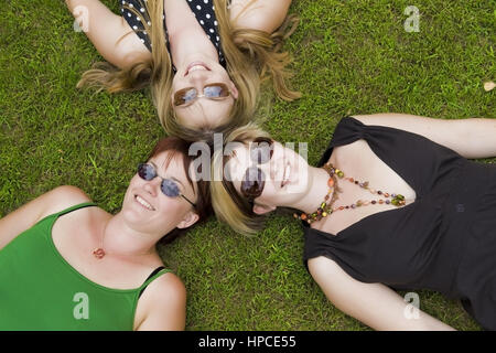 Modell veröffentlicht, Drei Frauen Mit Sonnenbrillen Stück Kopf ein Kopf in der Wiese - Frauen liegen auf der Wiese Stockfoto