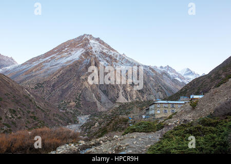 Touristen-Lodge auf dem Annapurna Circuit Trek mit schneebedeckten Bergen im Hintergrund im Himalaya, Nepal Stockfoto