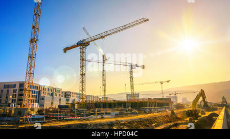 Große Baustelle einschließlich mehrerer Krane auf einen Gebäudekomplex mit klaren, blauen Himmel und die Sonne Stockfoto