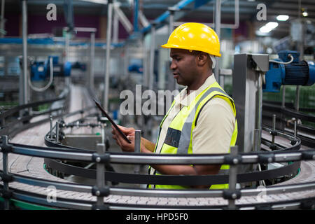 Fabrikarbeiter, die mit einem digitalen Tablet in der Nähe der Produktionslinie im Werk Stockfoto