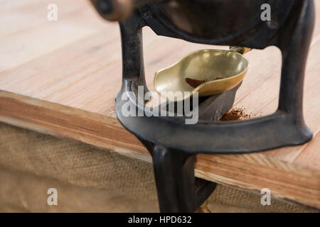 Kaffeemühle mit Schaufel und Kaffee-Pulver auf Tisch Stockfoto