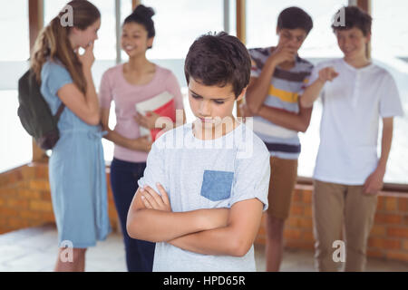 Schulfreunde Mobbing einen traurigen jungen im Korridor in der Schule Stockfoto