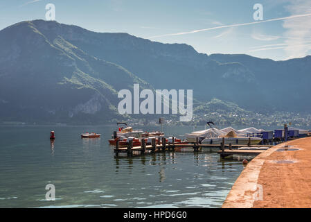 Annecy, Frankreich - 25. Mai 2016: Schöne Aussicht auf den Annecy-See in den französischen Alpen, ein Frühlingstag mit den Bergen im Nebel und Boote in den foregrou Stockfoto