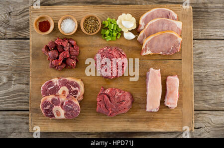 Sorten von Fleisch und Gewürzen auf Holztablett aus Holz Hintergrund Stockfoto