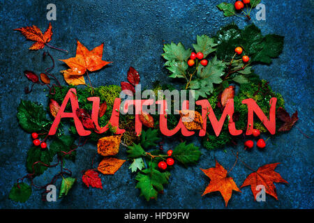 Herbst-Schriftzug mit Blättern und Eicheln auf dunklem Marmor Hintergrund. Buchstaben bestehen aus pastellfarbenen Papier.