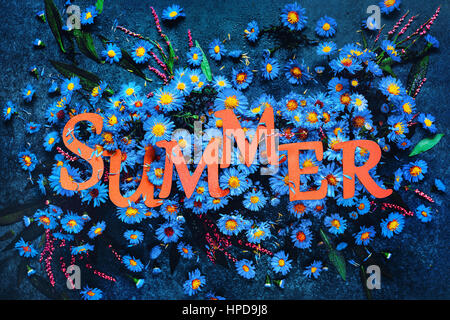Sommer-Schriftzug mit blauen vereinzelte Blüten auf dunklem Marmor Hintergrund. Buchstaben bestehen aus pastellfarbenen Papier.