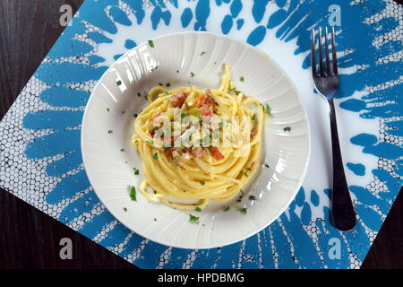 Vegetarische Carbonara - Zucchini (Zucchini) und Ei Spaghetti Pasta - Veggie italienisches Rezept serviert mit Gabel auf weißen und hellen blauen Tischset Stockfoto