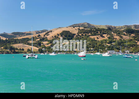 Akaroa, Canterbury, Neuseeland. Blick auf das türkisfarbene Wasser der Hafen von Akaroa, auf den sanften Hügeln des Banks Halbinsel. Stockfoto