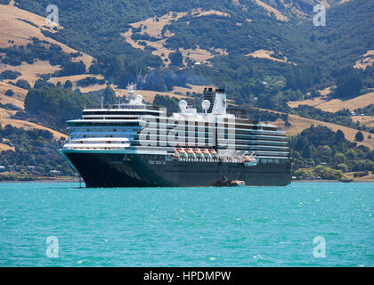 Akaroa, Canterbury, Neuseeland. Der Holland America Line Kreuzfahrtschiffe Oosterdam im Hafen von Akaroa, unterhalb der Hügel der Banken Halbinsel verankert. Stockfoto