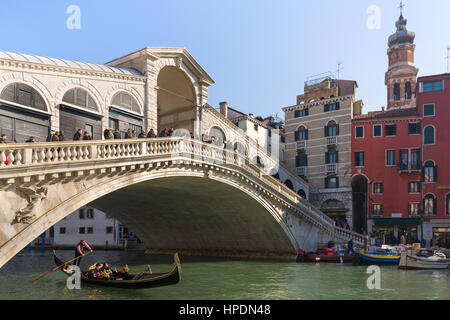 ein Gondoliere sieht man die zwei Passagiere in einer Gondel unter der Rialtobrücke in Venedig Stockfoto