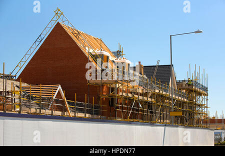 Neubaugebiet in UK zeigt Häuser und Dächer im Bau mit Gerüsten, Dachstühle, Dachgauben und Sparren am blauen Himmel Stockfoto