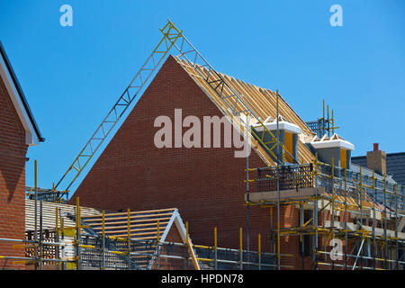 Neue Wohnsiedlung im Bau, zeigen neue Häuser mit Dächern, Dach Sparren, Gerüstbau, Hölzer und Sicherheit Ausrüstung und blauer Himmel Stockfoto