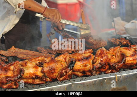 Straßenverkäufer an einem Open-Air BBQ Chicken Street Stand mit einem Basting Pinsel, um das Fleisch zu marinieren, Kandal Market, Phnom Penh, Kambodscha. © Kraig Lieb Stockfoto