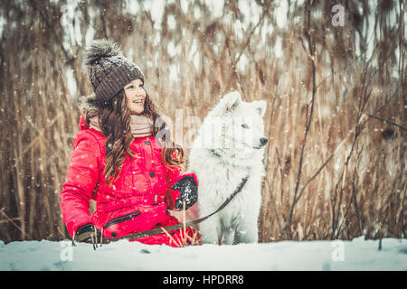 Glückliches Mädchen mit Hund im Winter Wald Stockfoto