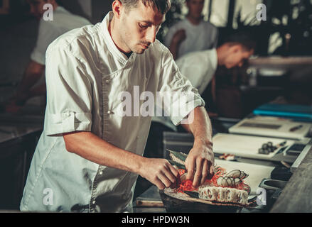 Küchenchef im Hotel oder Restaurant Küche Dekoration Gericht. Er arbeitet an Maki-Rollen. Vorbereitung Sushi set Stockfoto