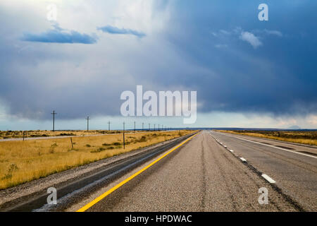 Eine leere zweispurige amerikanischen mittleren Westen Autobahn erstreckt sich in die Ferne, während Gewitterwolken über Kopf bedrohen. Stockfoto