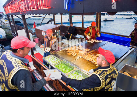 Tarihi Eminonu Balikcisi Deniz Yildici (Boot-Stall). Frisch gebratene Fische wird Hammer auf einem Boot in Eminönü, vor der Galata-Brücke, Istanbul, Tu Stockfoto