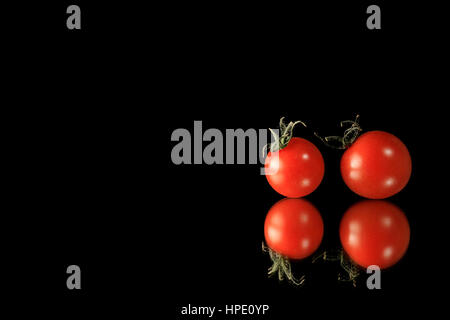 rote Tomate auf Reflexion schwarz Stockfoto