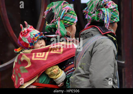 SA PA - 23. Februar 2013: Eine unbekannte Hmong Frau mit ihrem Kind in ihrer Babytrage in Nordvietnam. Die Hmong sind eines der größten Stockfoto