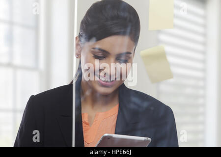 Geschäftsfrau hinter Glasscheibe mit Klebstoff Noten mit digital-Tablette in office Stockfoto