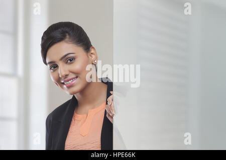 Geschäftsfrau hinter Glasscheibe Blick in die Kamera Lächeln Stockfoto